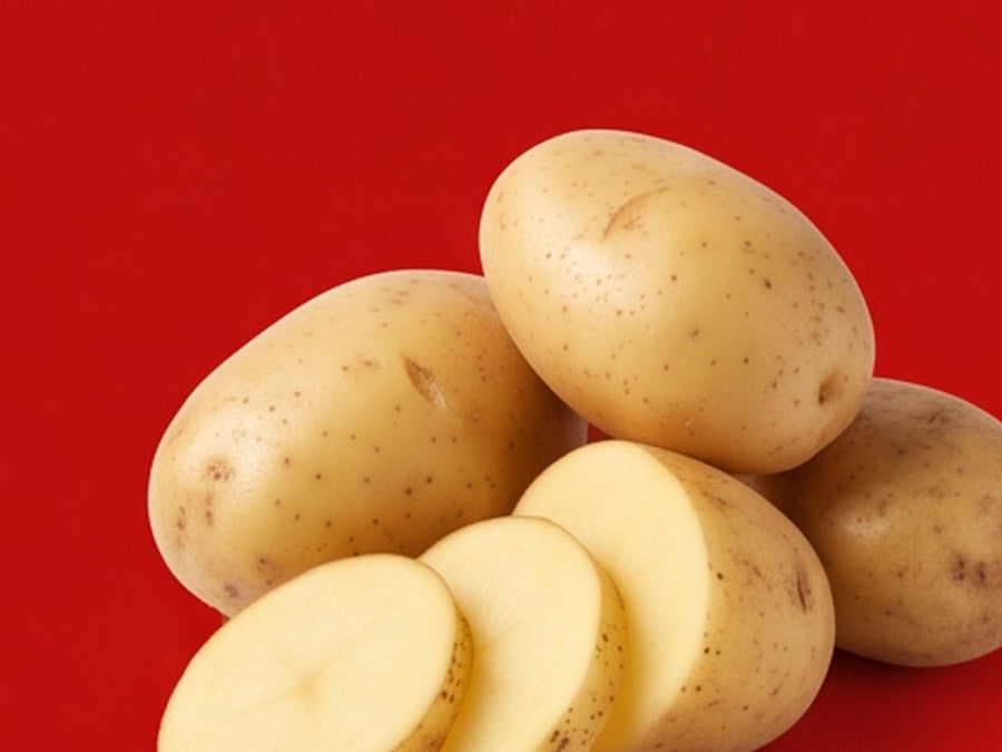 Whole and sliced yellow potatoes on a red background